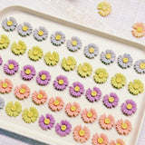 Handmade daisy-shaped chicken cookies with yellow, purple, pink and orange petals on a white plate