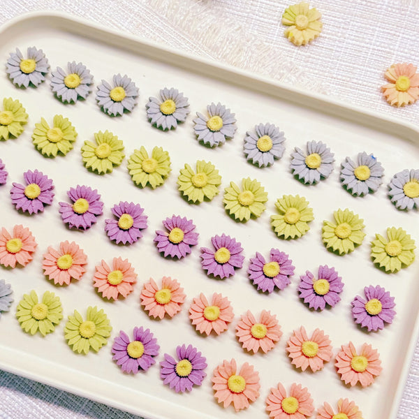 Handmade daisy-shaped chicken cookies with yellow, purple, pink and orange petals on a white plate