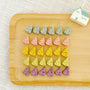 Tiny swiss-cheese wedge shaped chicken cookies in gray, pink, yellow, green and purple on a white plate