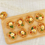 Close-up of the tiny ramen bowl dog treat showing the egg yolk topping and vegetable details