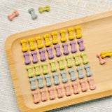 Extra-mini rainbow bone-shaped chicken cookies in yellow, purple, green, blue and pink on a white plate